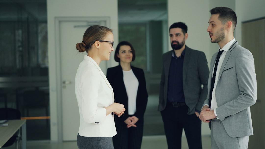 Happy guy in trendy suit is getting job in company after successful interview, shaking hands and smiling expressing excitement while people are clapping hands congratulating him.